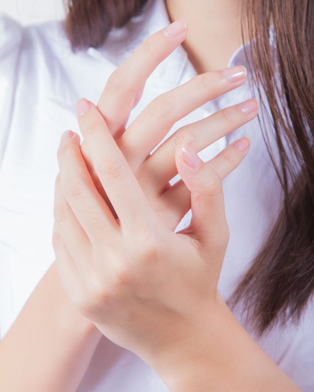 Des mains délicates croisées sur une chemise blanche