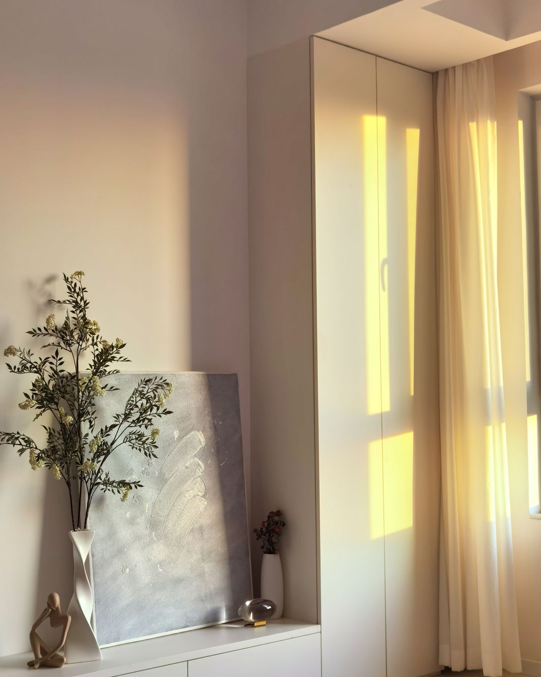 Un intérieur baigné de lumière naturelle, une branche d'olivier dans un vase